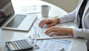 A tax professional and a Massachusetts business owner reviewing vendor tax forms and payment records under the 2026 1099 reporting threshold rules.
